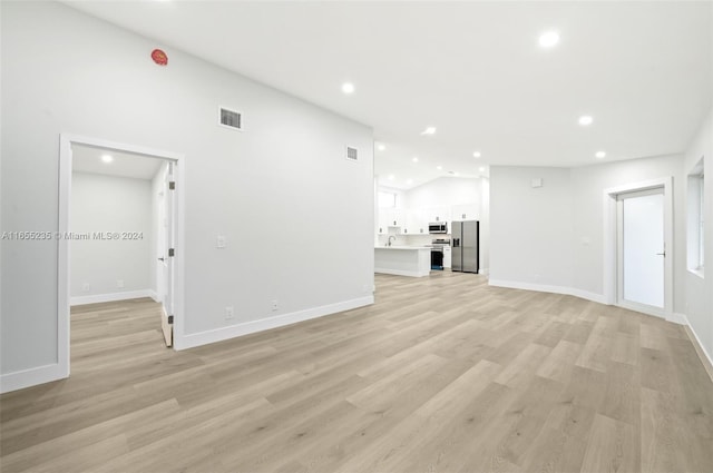 unfurnished living room featuring light wood-type flooring and lofted ceiling