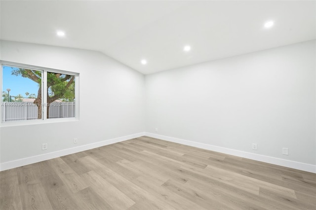 spare room with light wood-type flooring and vaulted ceiling