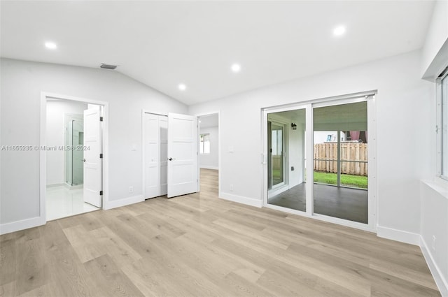 unfurnished bedroom featuring ensuite bathroom, light hardwood / wood-style floors, lofted ceiling, and access to outside