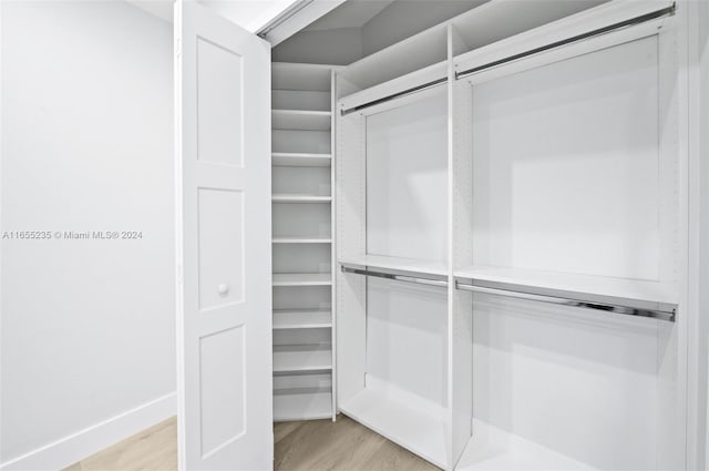 walk in closet with light hardwood / wood-style flooring