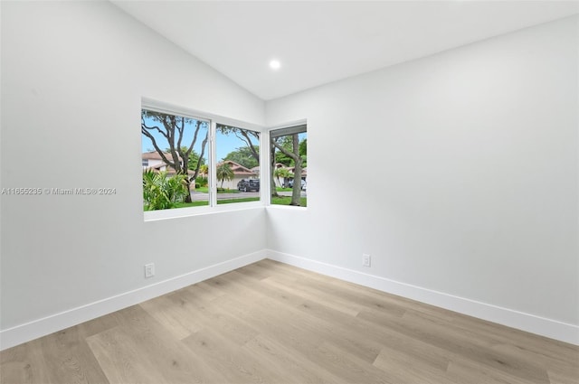 spare room with light hardwood / wood-style floors and lofted ceiling