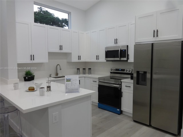 kitchen with sink, kitchen peninsula, light hardwood / wood-style floors, white cabinetry, and stainless steel appliances