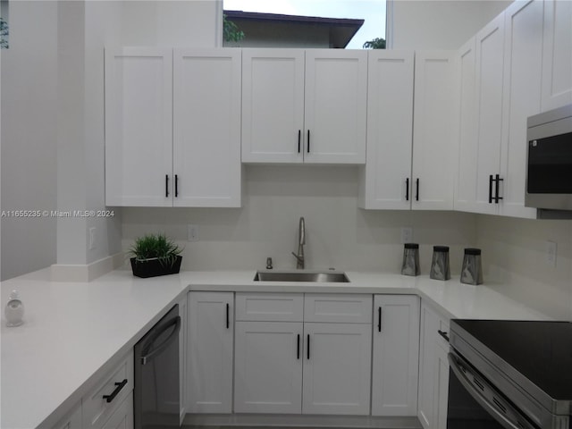 kitchen with stainless steel appliances, white cabinetry, and sink