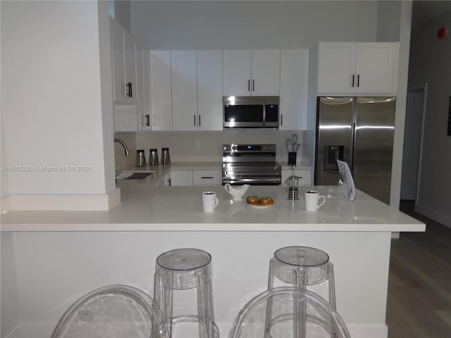 kitchen with white cabinets, a kitchen breakfast bar, sink, and appliances with stainless steel finishes