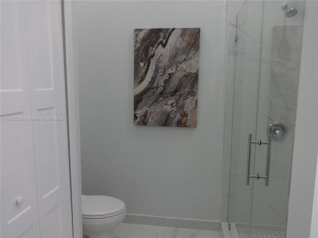 bathroom featuring toilet and a shower with shower door