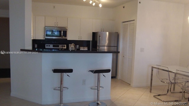 kitchen featuring appliances with stainless steel finishes, sink, light tile patterned floors, and white cabinets