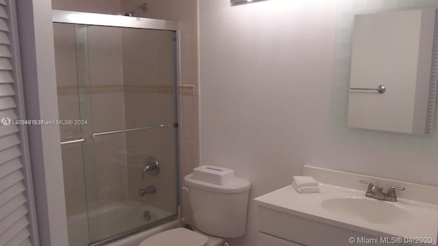 full bathroom featuring enclosed tub / shower combo, toilet, and vanity