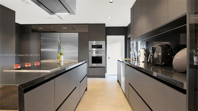 kitchen with dark stone countertops, sink, appliances with stainless steel finishes, and light tile patterned flooring