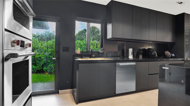 kitchen with light tile patterned floors, stainless steel oven, and sink