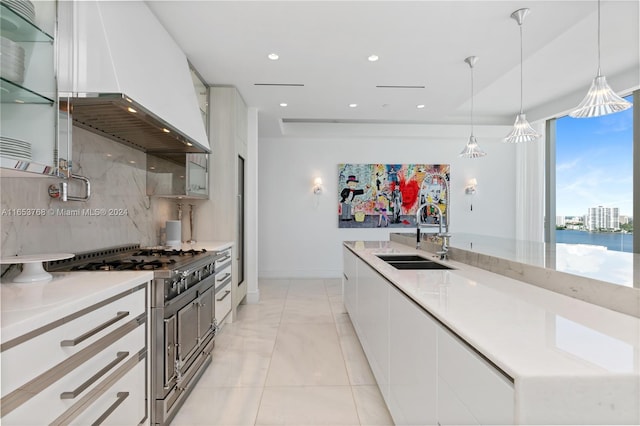 kitchen with pendant lighting, range with two ovens, white cabinetry, sink, and custom range hood