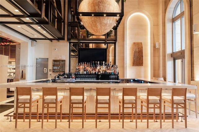 bar with a high ceiling and light parquet floors