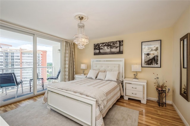 bedroom featuring light wood-type flooring, access to exterior, and a chandelier