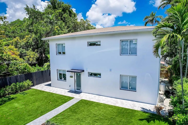 back of property with a yard and a patio