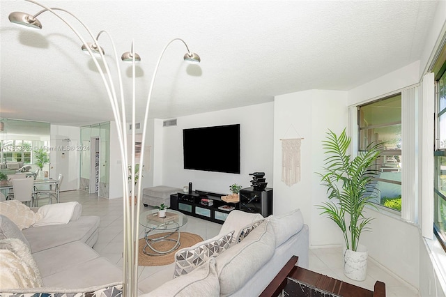 tiled living room featuring a textured ceiling and a healthy amount of sunlight