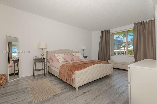 bedroom with a textured ceiling and light hardwood / wood-style floors