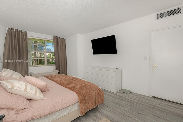 bedroom with a textured ceiling and light wood-type flooring