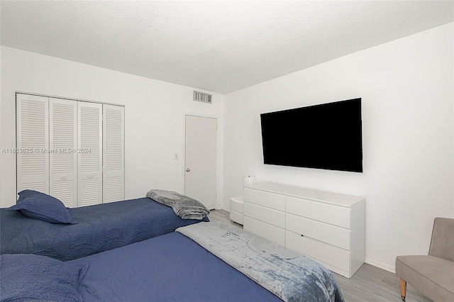 bedroom featuring light hardwood / wood-style floors, a textured ceiling, and a closet