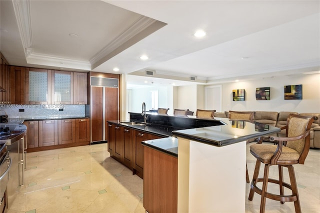 kitchen featuring paneled refrigerator, a tray ceiling, sink, and a kitchen island