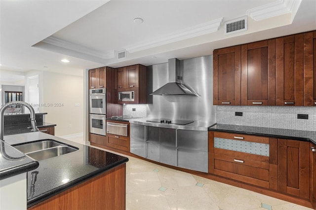 kitchen with decorative backsplash, a raised ceiling, wall chimney exhaust hood, stainless steel appliances, and ornamental molding