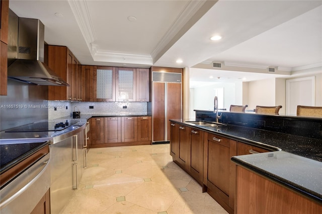 kitchen featuring sink, tasteful backsplash, wall chimney exhaust hood, black electric cooktop, and paneled built in fridge