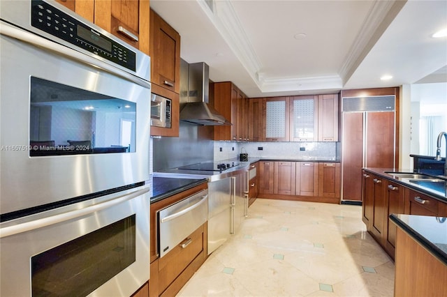 kitchen with sink, tasteful backsplash, wall chimney range hood, paneled built in fridge, and stainless steel double oven