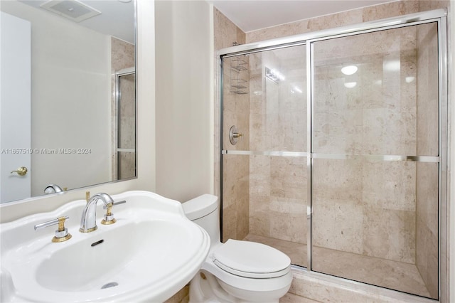 bathroom with a shower with door, toilet, and sink