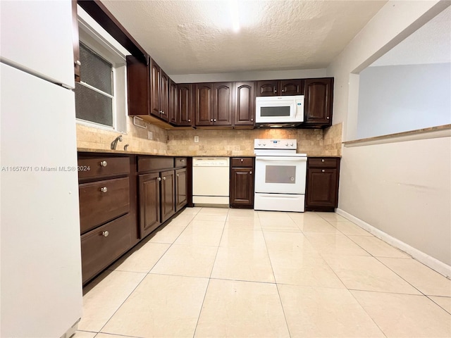 kitchen featuring dark brown cabinets, a textured ceiling, tasteful backsplash, white appliances, and light tile patterned floors