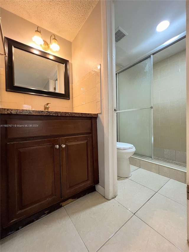 bathroom featuring vanity, a textured ceiling, tile patterned floors, walk in shower, and toilet