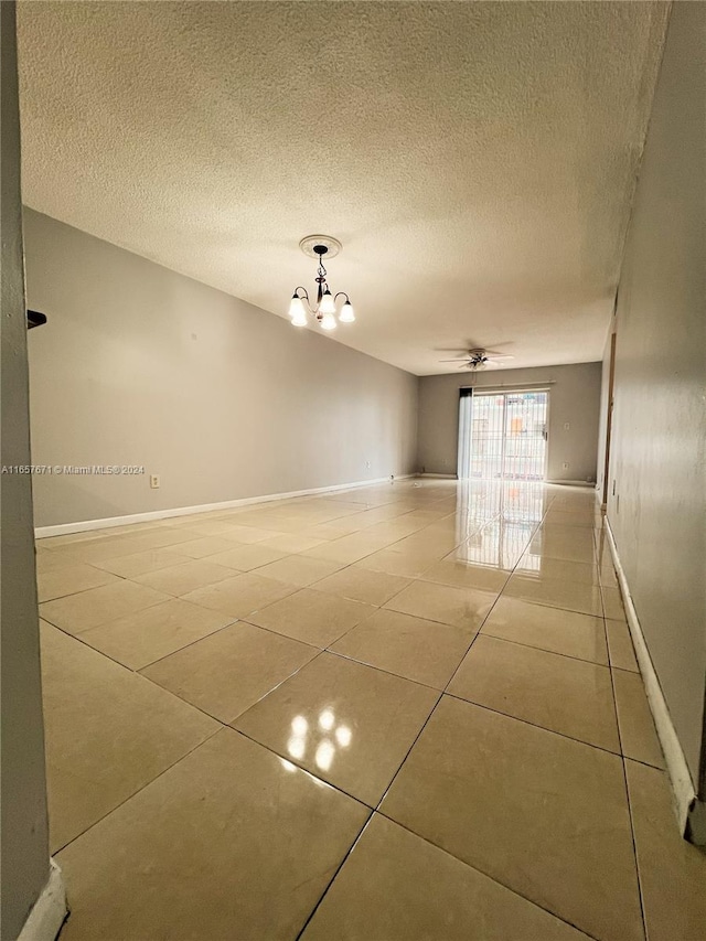 unfurnished room with a textured ceiling, ceiling fan with notable chandelier, and light tile patterned floors