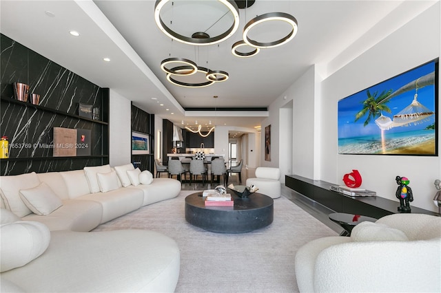 living room with a raised ceiling and a chandelier