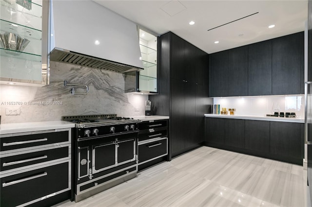 kitchen with decorative backsplash, exhaust hood, and range with two ovens