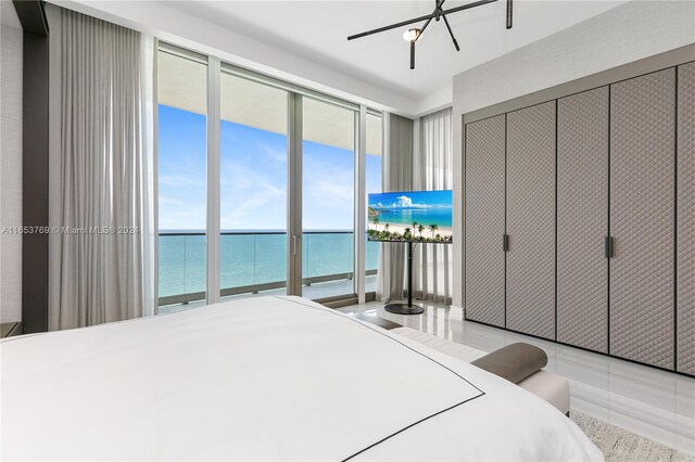 bedroom featuring a closet, access to exterior, a water view, light tile patterned floors, and ceiling fan