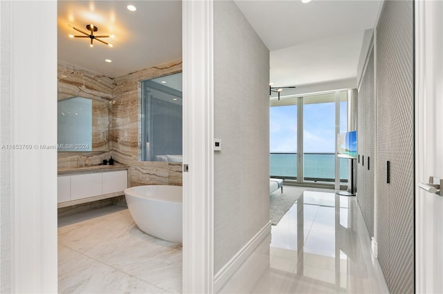 bathroom featuring tile patterned flooring, a water view, a washtub, and vanity