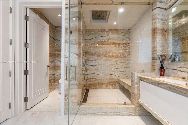 bathroom featuring tile walls, a shower with door, vanity, and toilet