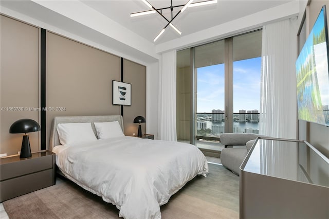 bedroom featuring light hardwood / wood-style floors, a chandelier, multiple windows, and access to exterior