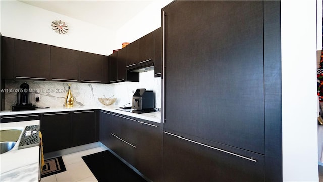 kitchen featuring range hood, black gas stovetop, backsplash, light tile patterned floors, and dark brown cabinetry