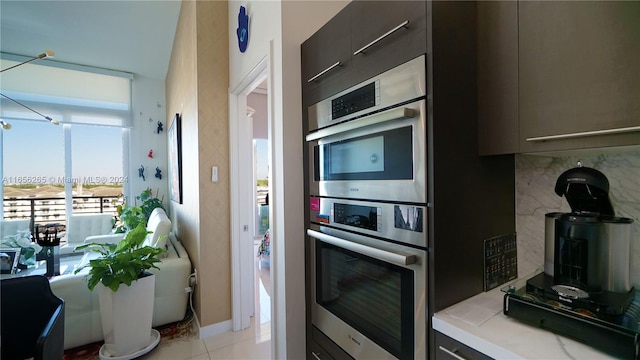 kitchen with light tile patterned flooring, stainless steel double oven, and tasteful backsplash