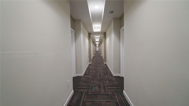 hallway featuring dark colored carpet