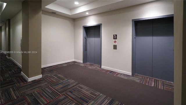 hallway with dark colored carpet and elevator