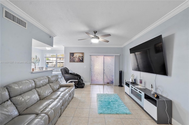 tiled living room with ceiling fan, ornamental molding, and a textured ceiling