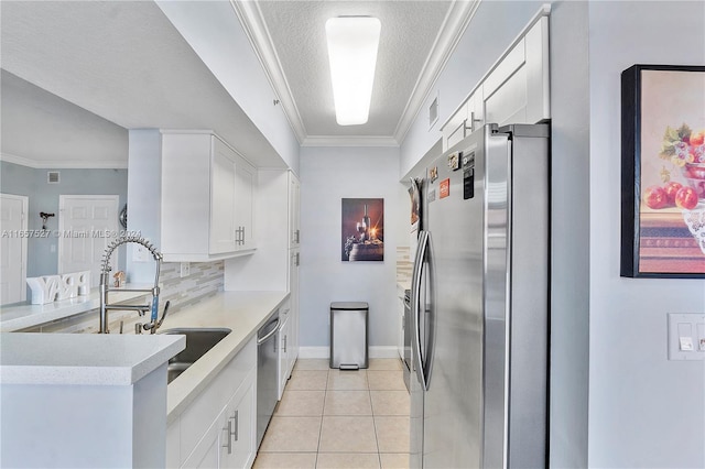 kitchen with light tile patterned floors, stainless steel appliances, white cabinetry, and crown molding