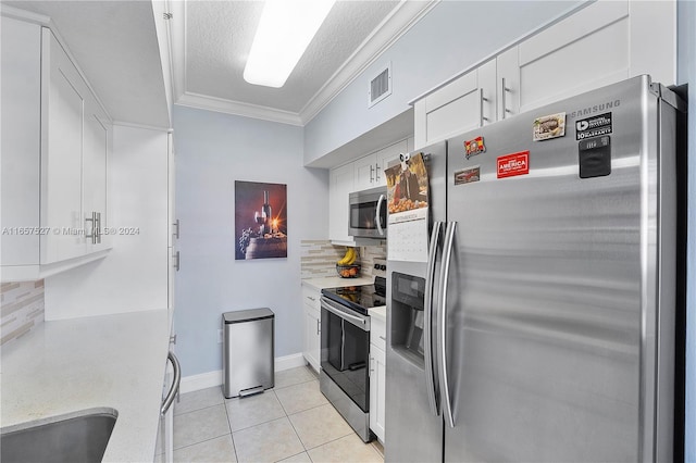 kitchen featuring white cabinets, crown molding, light tile patterned floors, appliances with stainless steel finishes, and tasteful backsplash