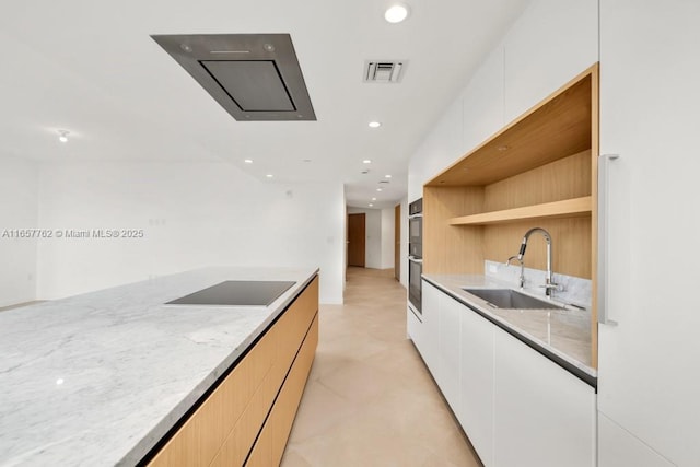 kitchen featuring a sink, visible vents, light stone countertops, black appliances, and modern cabinets