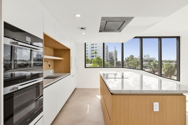 kitchen with a view of city, visible vents, white cabinets, a sink, and modern cabinets