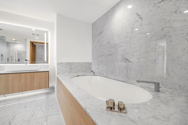 bathroom with marble finish floor, a garden tub, and vanity