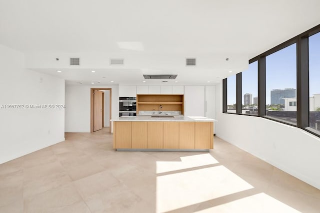 kitchen featuring a spacious island, double oven, and sink