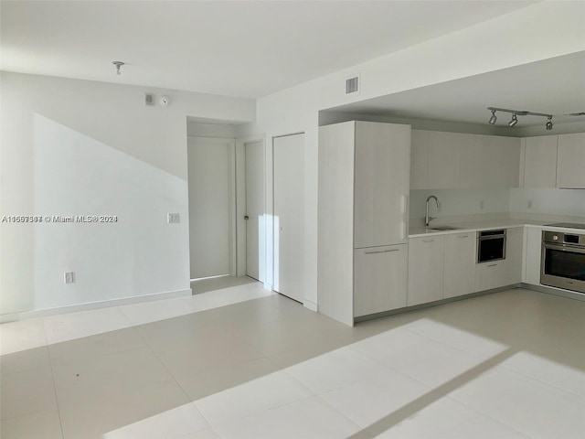 kitchen featuring sink, oven, and light tile patterned flooring