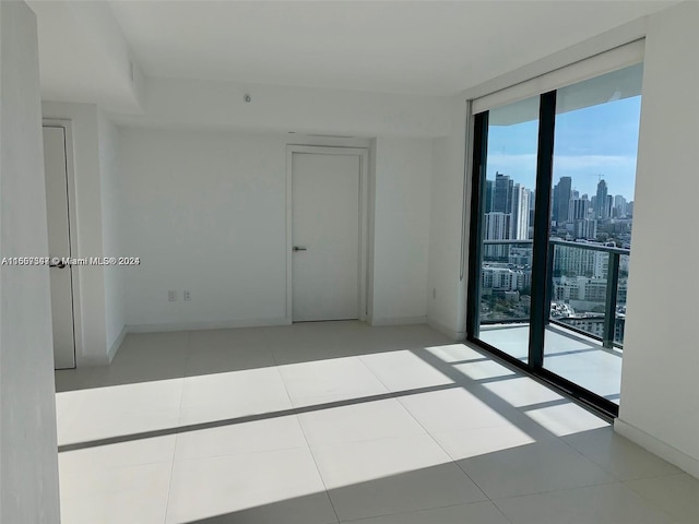 empty room featuring light tile patterned flooring and a wall of windows