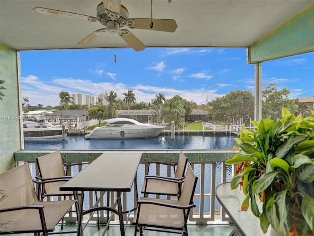 balcony featuring a dock, a water view, and a ceiling fan