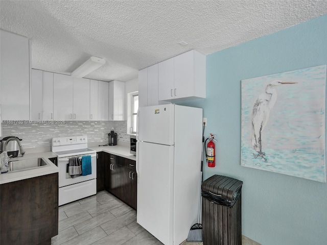 kitchen featuring backsplash, light countertops, white appliances, white cabinetry, and a sink